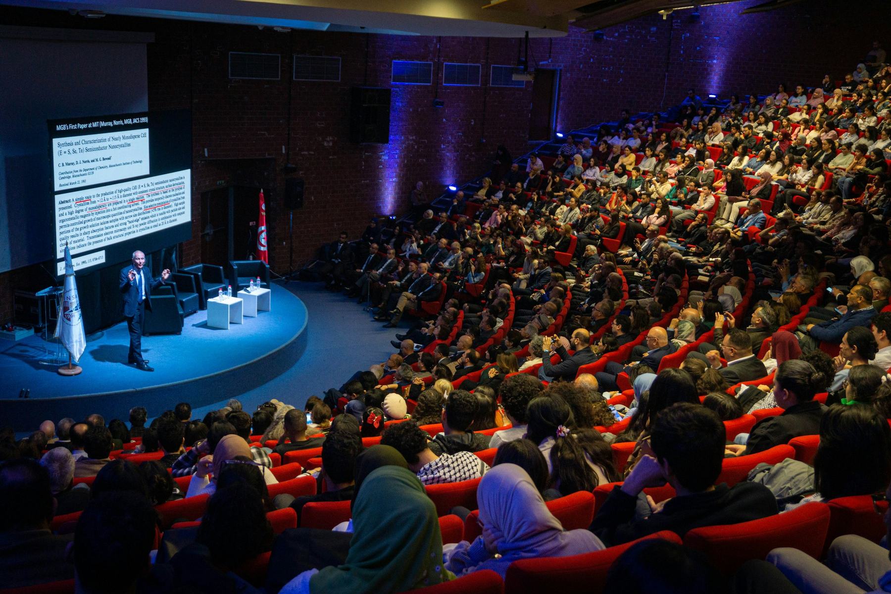 A speaker presenting to an audience in an auditorium