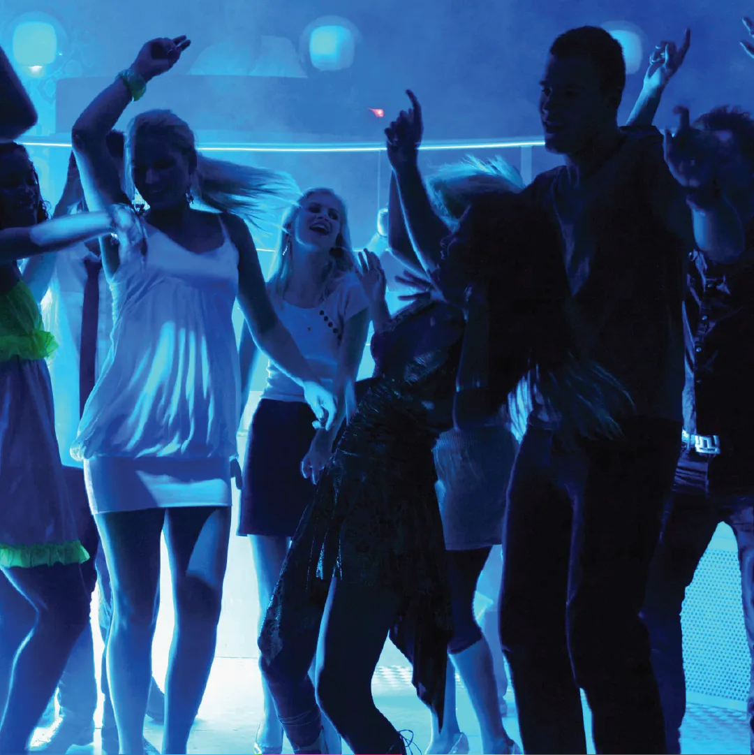A crowd dancing under blue lights at a night event